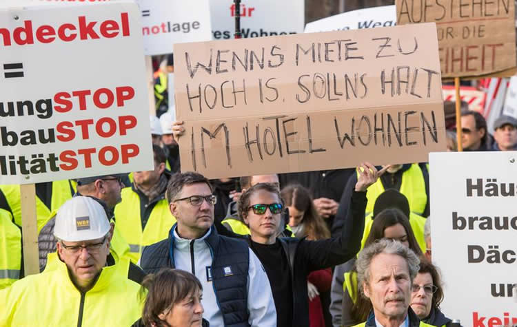德国房租高涨抗议者手持讽刺标语房租太贵就住宾馆